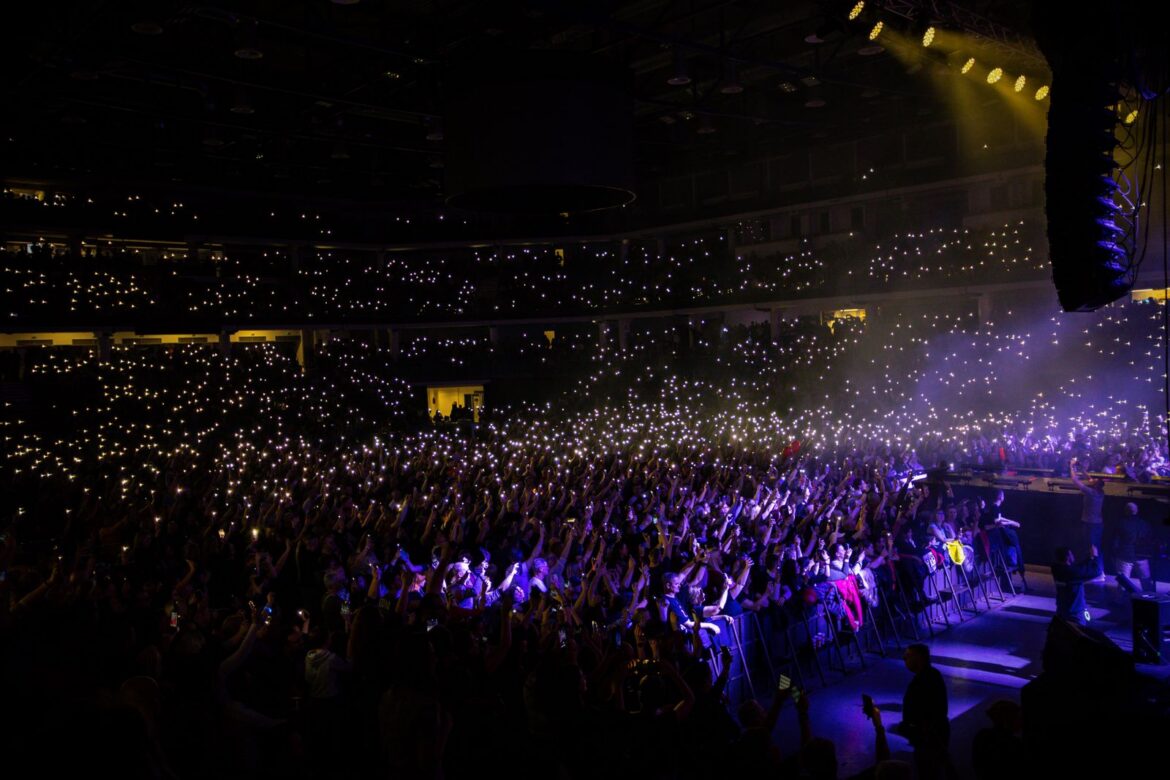 Crowd of K-pop fans holding light sticks at a concert