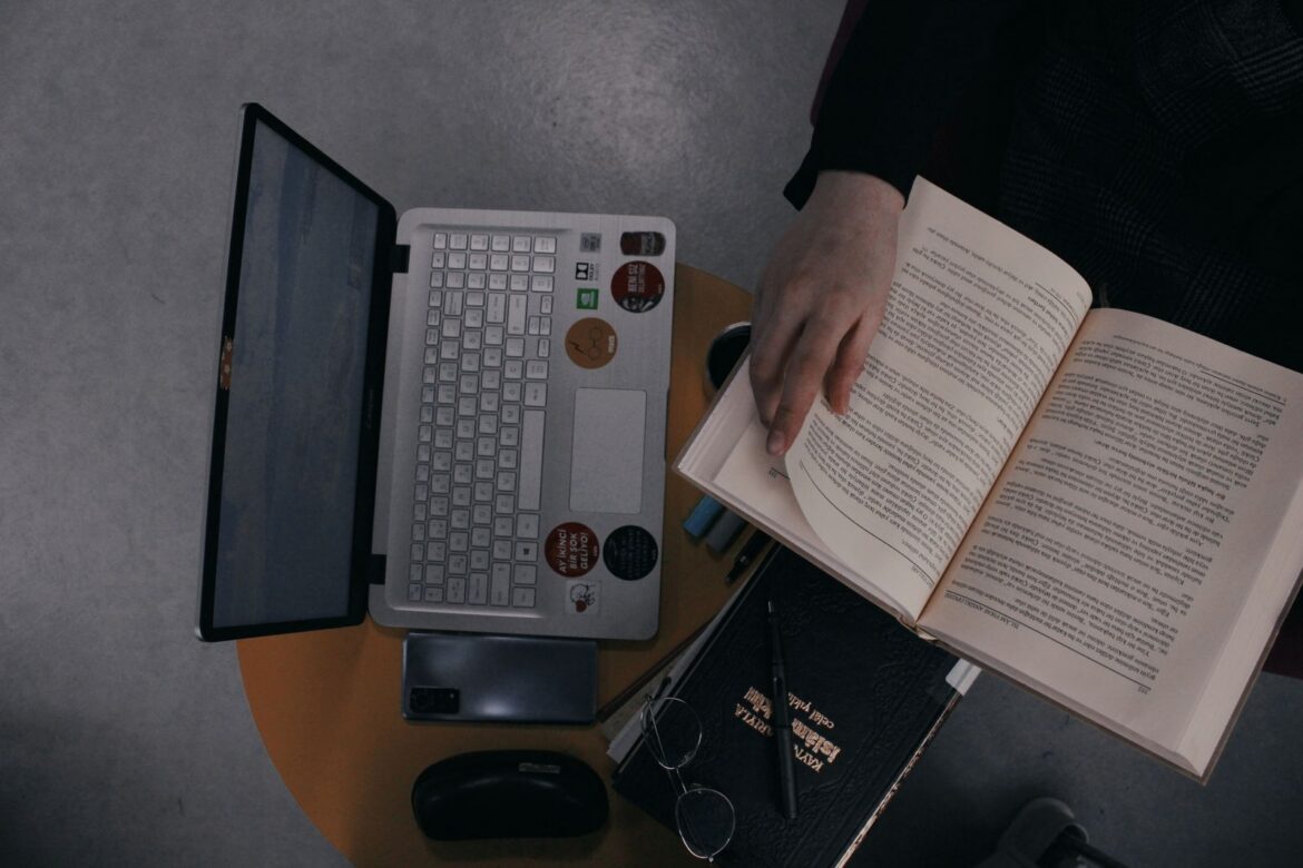 Person reading with laptop and open book