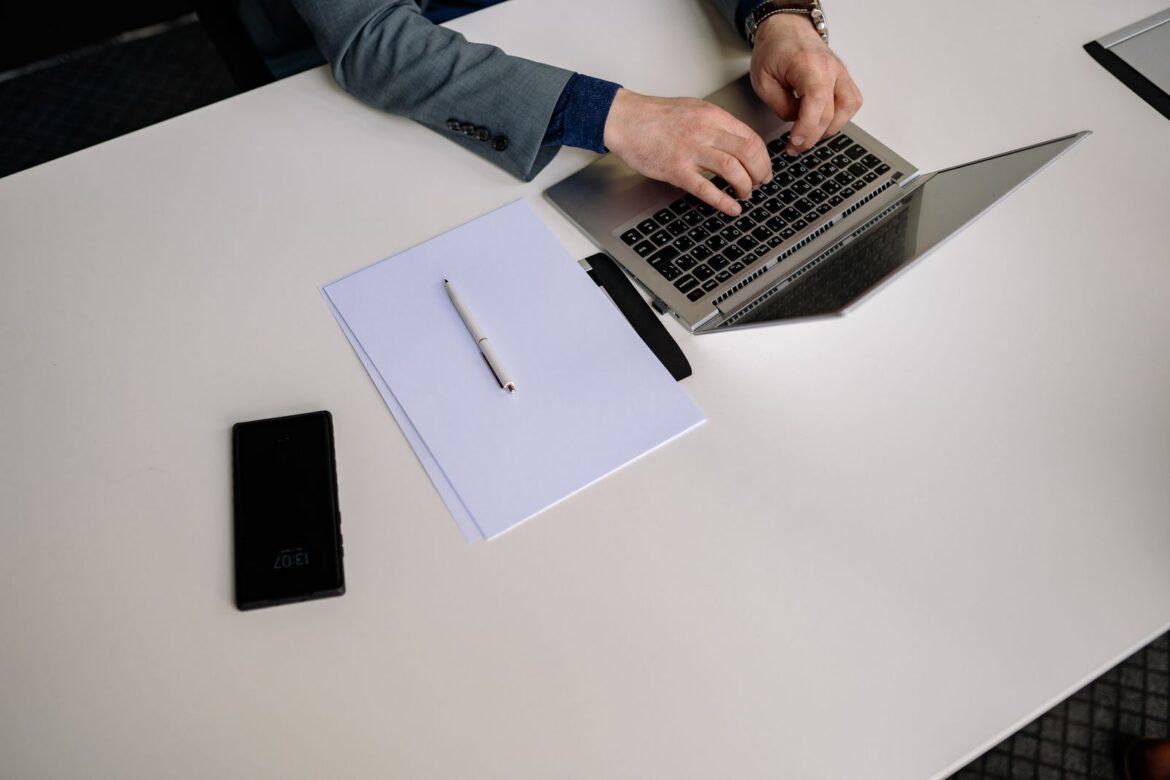 Top view of businessman typing on a laptop at a neat white desk