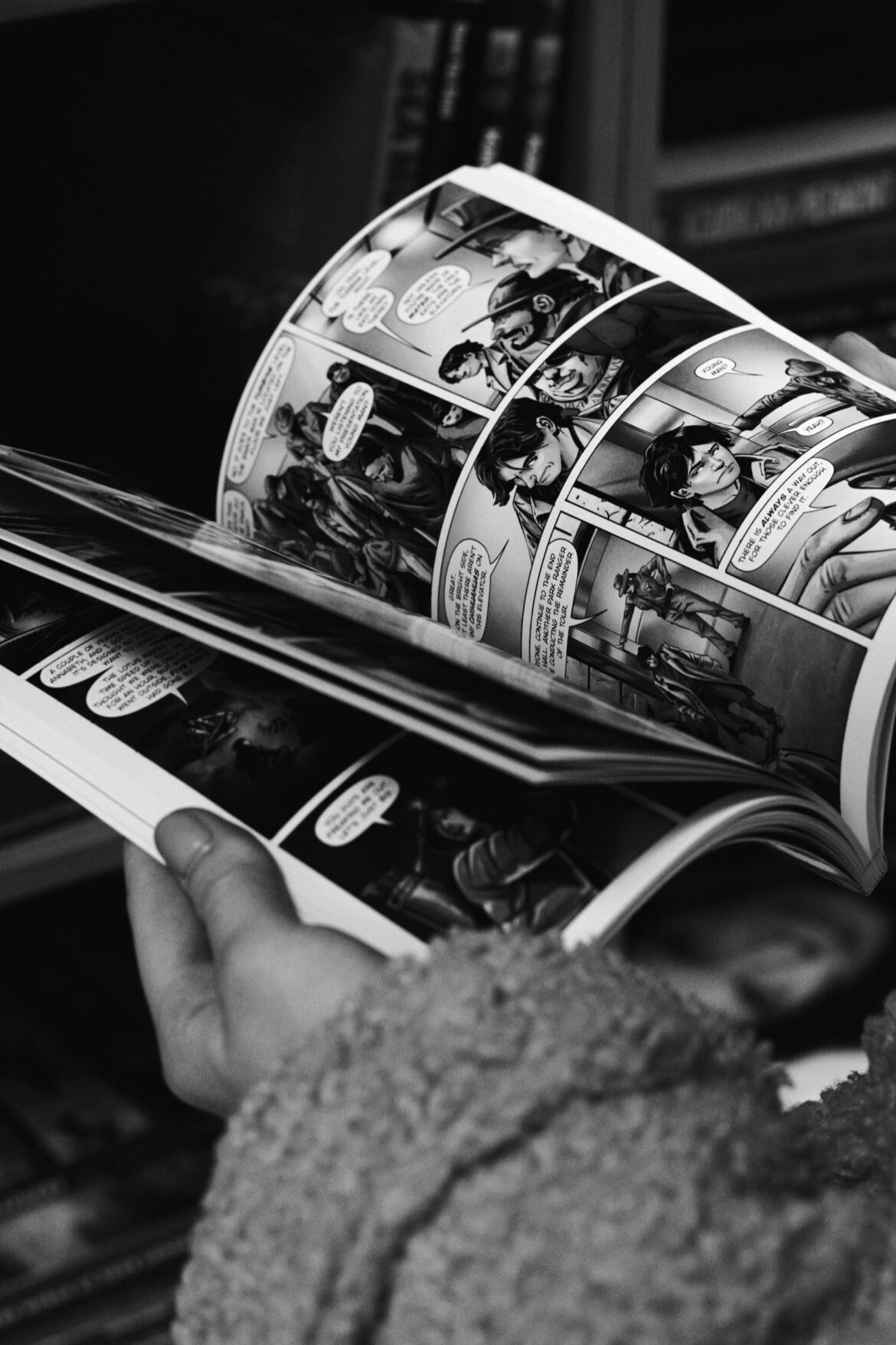 Hands reading black and white comic book panels