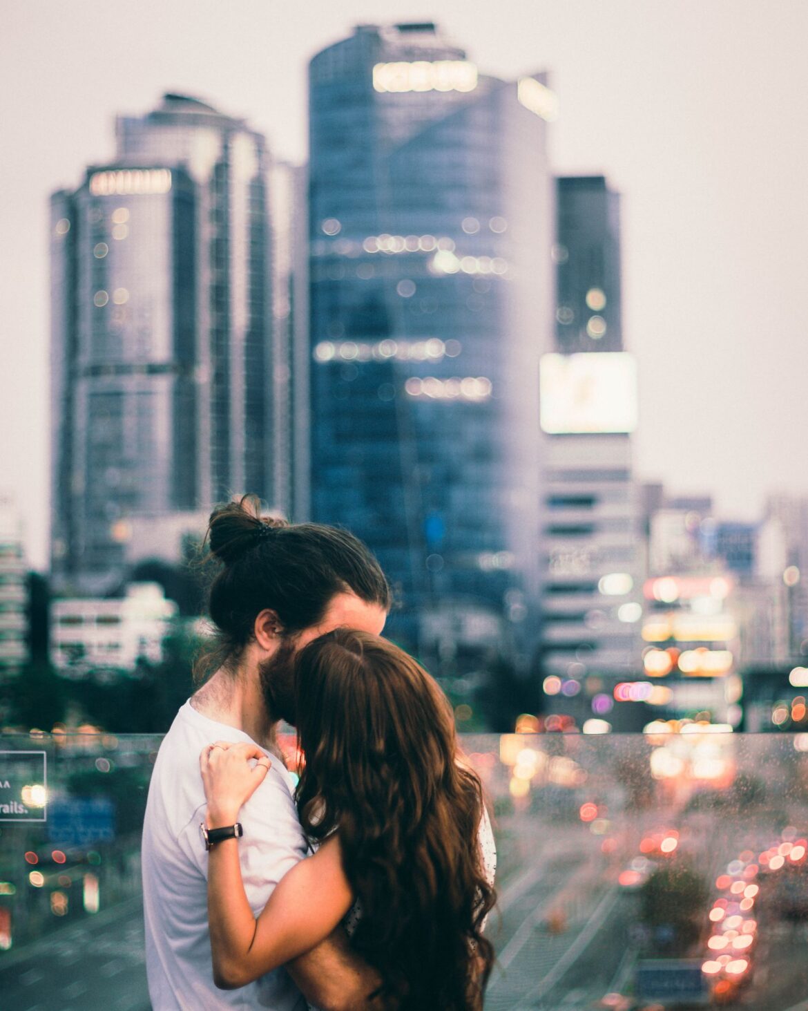 A couple shares a tender moment embracing with Seoul skyline in the twilight backdrop