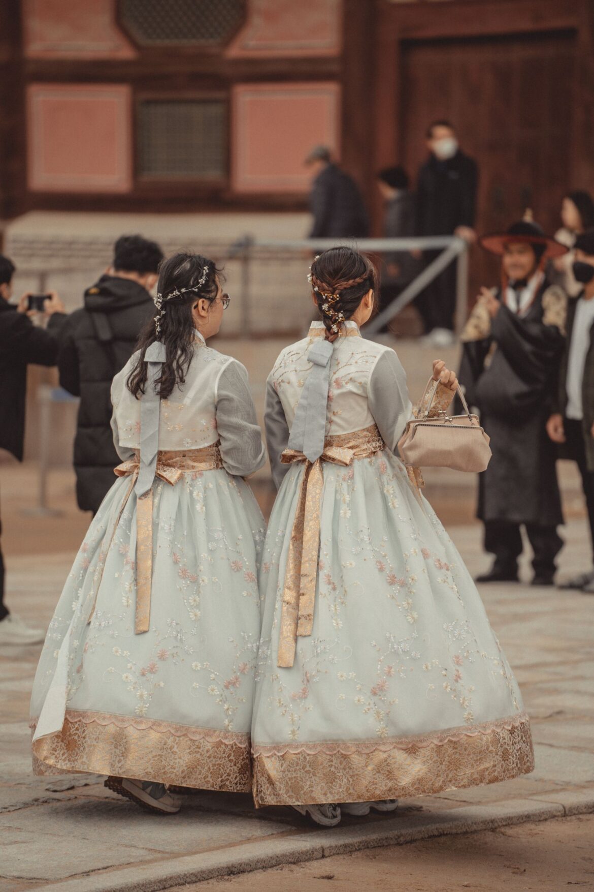 Women in traditional Korean clothing walking near a building