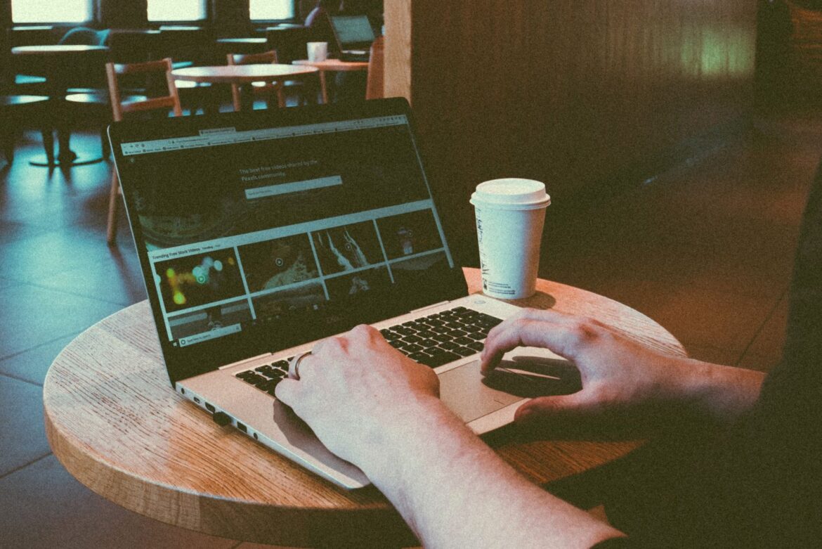 Person using a laptop in a cafe study-friendly seating area with coffee, representing Korea cafe focus zones