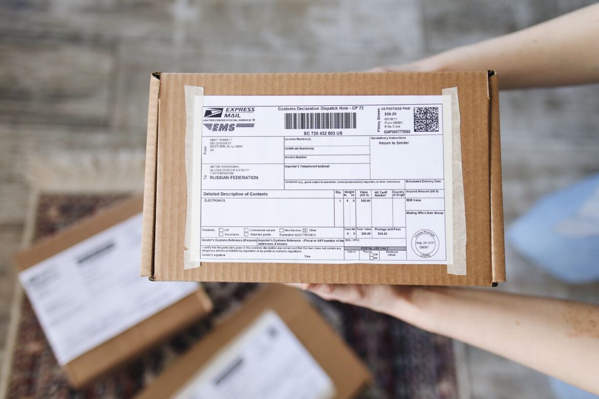 Hands holding an international express mail parcel with a customs declaration, representing Korea Post EMS shipping