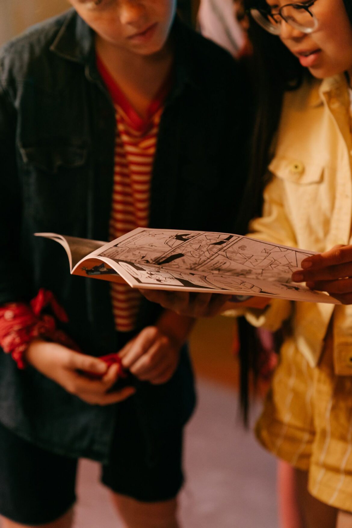 Teenagers reading comic book indoors